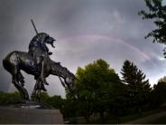 End of Trail Statue in front of rainbow