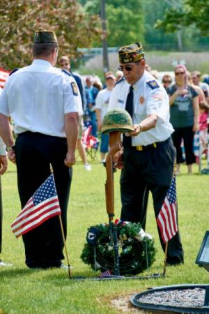 Veterans next to helmet on top of memorial